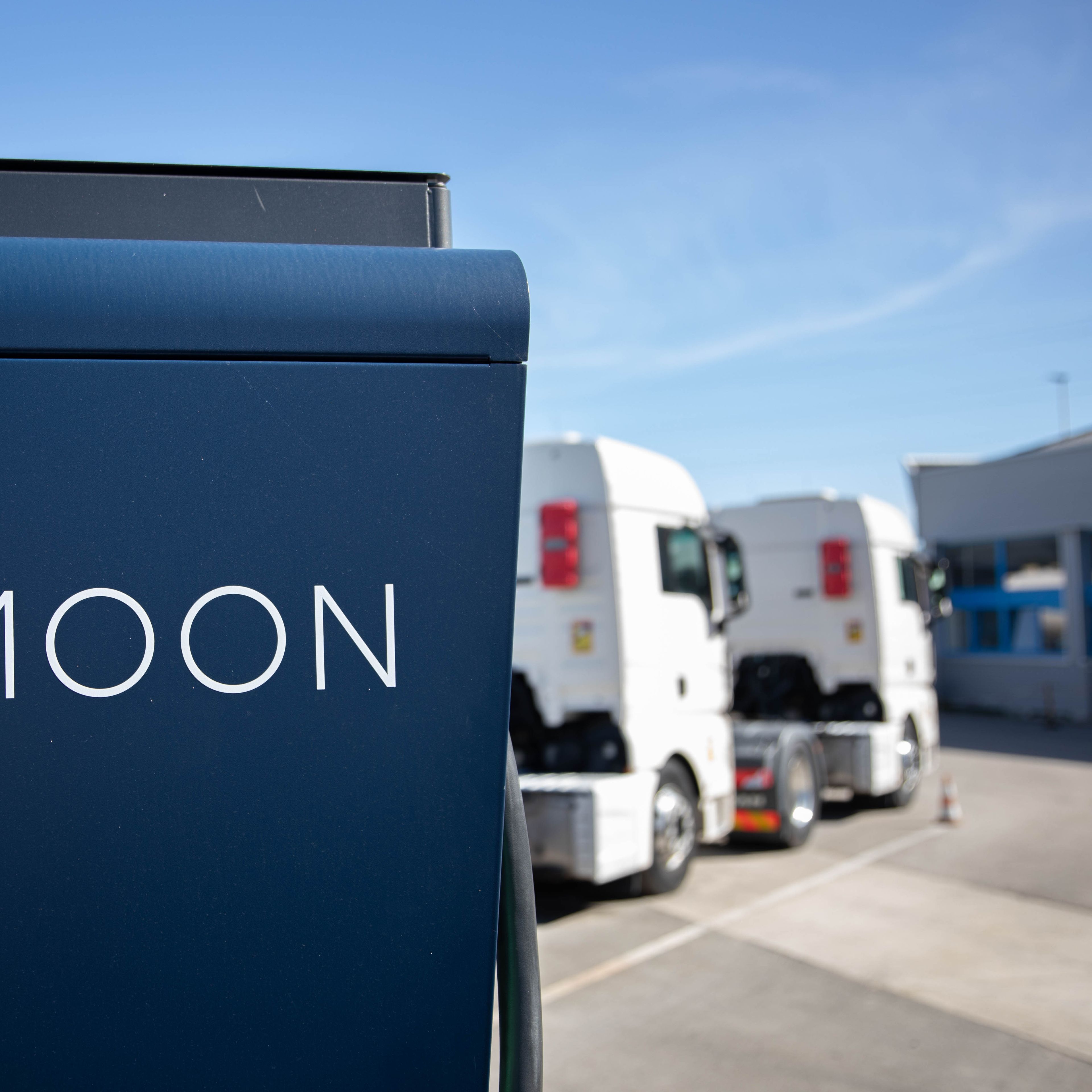 Dva tovornjaka sta parkirana za MOON HYC 200–400 hitro polnilno postajo.