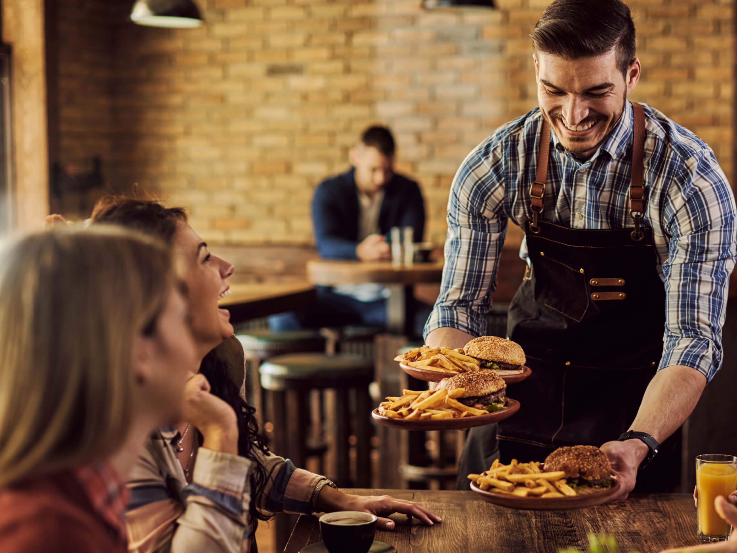 Kelnar v gostilni prinaša hrano gostom za mizo.