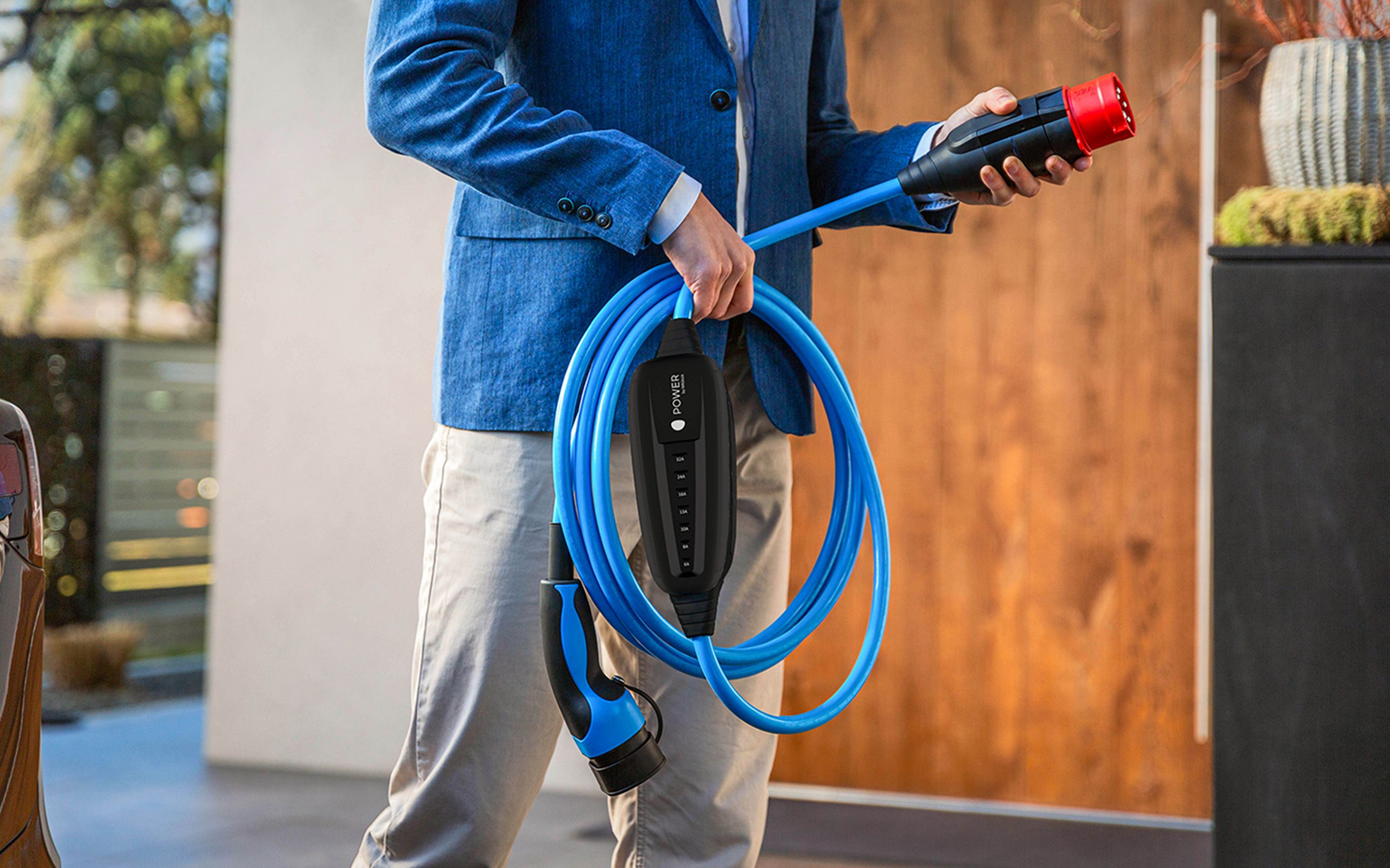 Moški drži priključek MOON POWER2Go polnilnega kabla v roki.