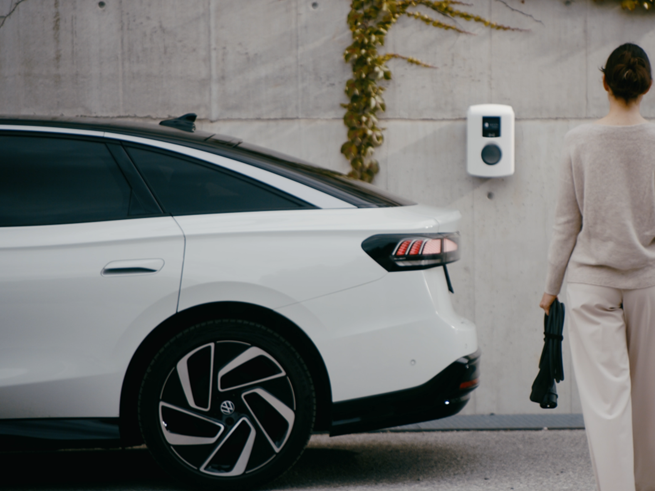 Ženska hodi proti stenski polnilni postaji