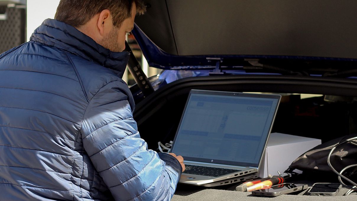 Moški z prenosnikom ob avtomobilu