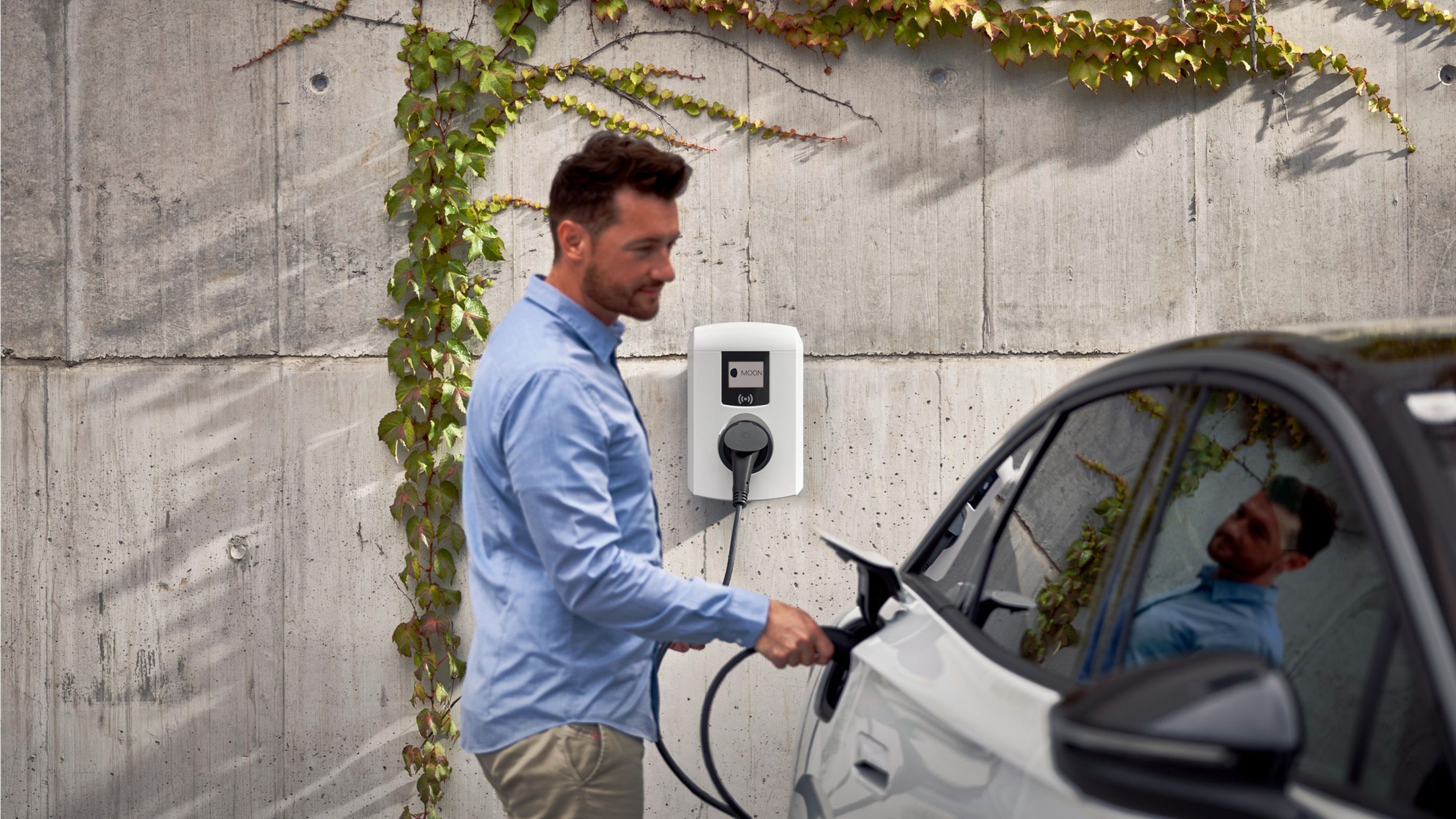 Man charging electric car with a wallbox