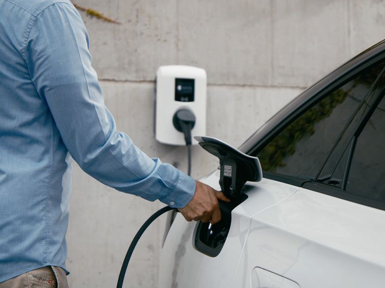 Oseba polni električni avtomobil na MOON stenski polnilnici.