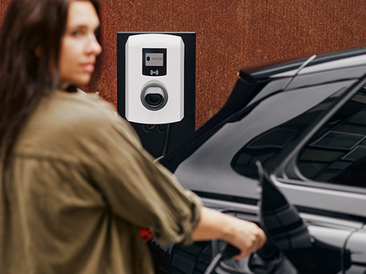 Ženska priključi polnilni kabel MOON stenske polnilnice v električni avtomobil.